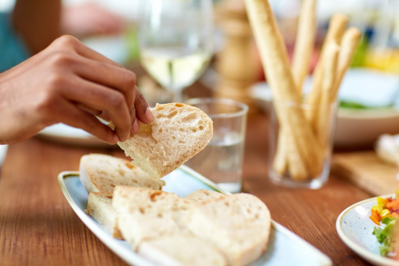 Henkilö ottaa leipäviipaleen leipälautaselta.